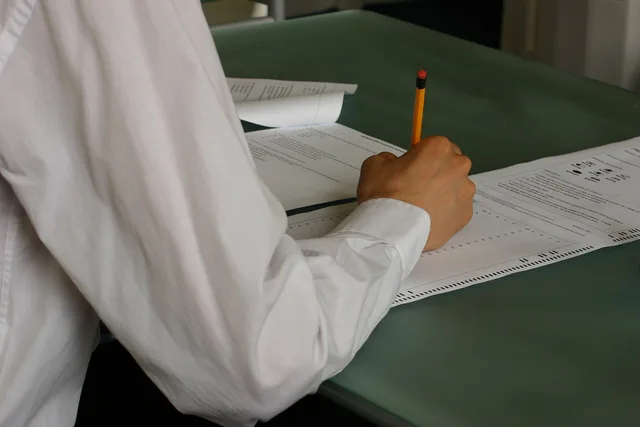 Student in a classroom writing exam papers. Career quizzes questions: How to pass the single-answer test