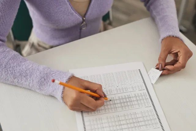 Close-up of a person using a cheat sheet while answering a multiple-choice exam. Daily and seasonal quizzes: build the bank before the schedule