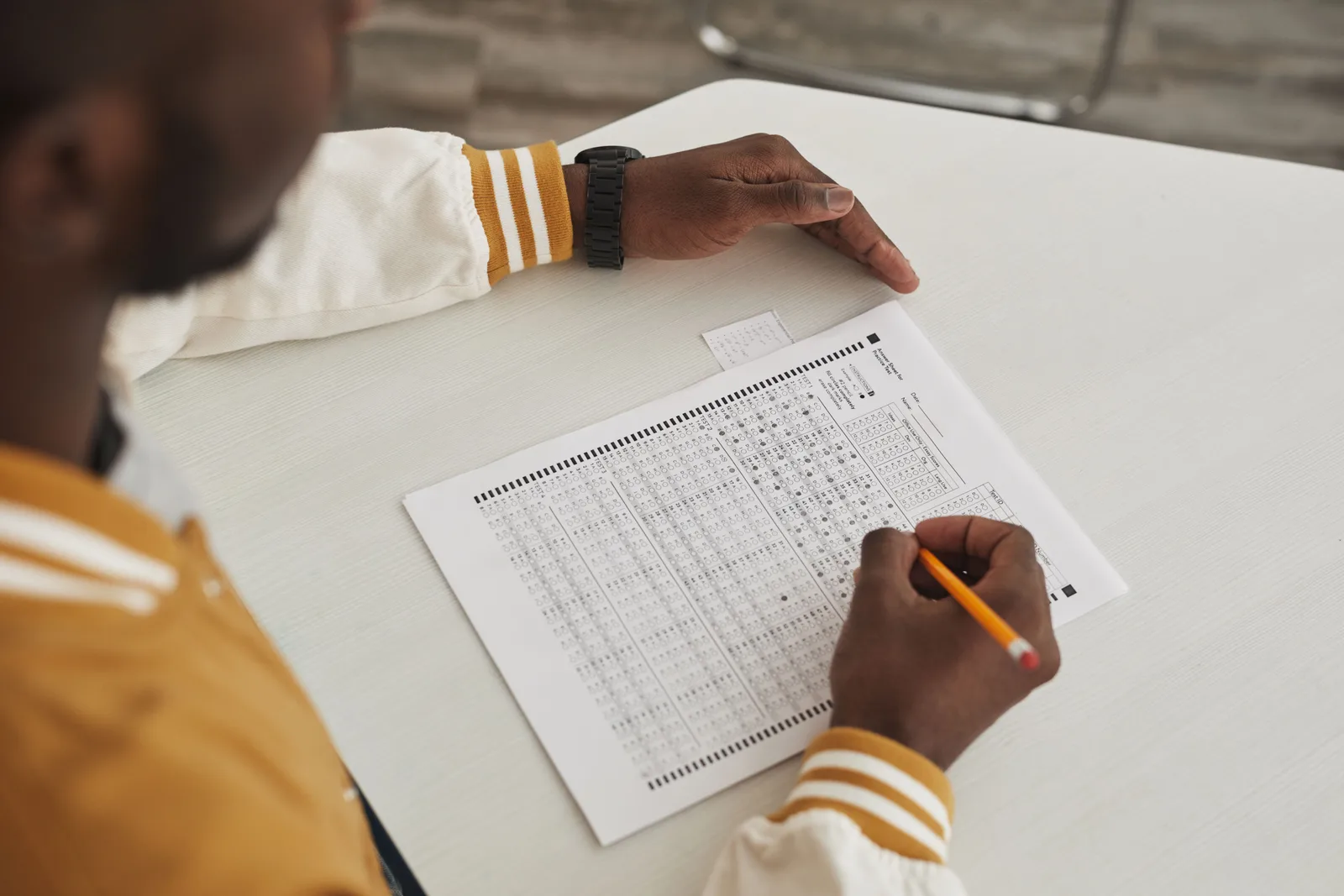 Focused student marking answers on a multiple choice exam sheet in a classroom setting. Photo quizzes: fairness depends on the instruction, not the picture