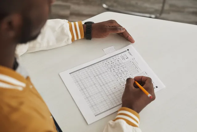 Focused student marking answers on a multiple choice exam sheet in a classroom setting. Photo quizzes: fairness depends on the instruction, not the picture