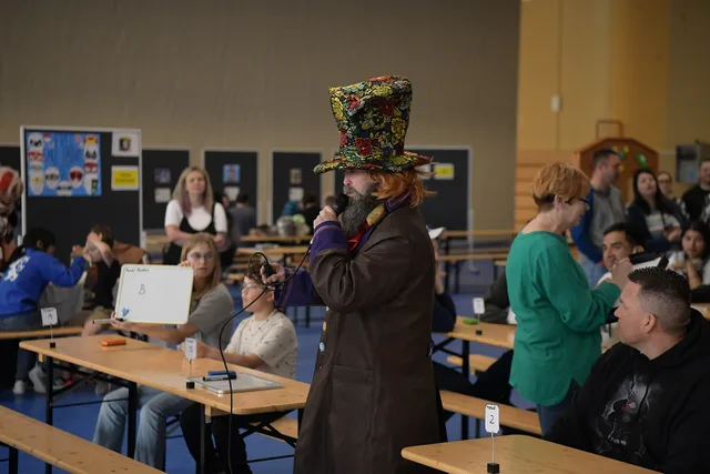 A game show host conducts a trivia contest at the Baumholder Comic Convention at the Hall of Champions in Baumholder, Germany, May 20, 2023. The trivia rounds alternated every hour and topics switched among popular comic book and popular culture franchises. (U.S. Air Force photo by Airman 1st Class. Popularity games by profession: rules for a fair round